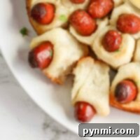 A delightful pull-apart ring of baked pigs in a blanket encircles a savory dip at the center, perfect for sharing.