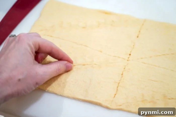Golden Air Fryer Pigs in Pastry 2 A hand pinching perforations on crescent rolls dough