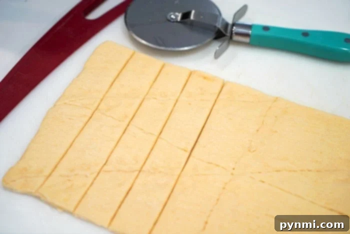 Golden Air Fryer Pigs in Pastry 3 Rolled-out crescent roll dough sliced into strips with a pizza cutter