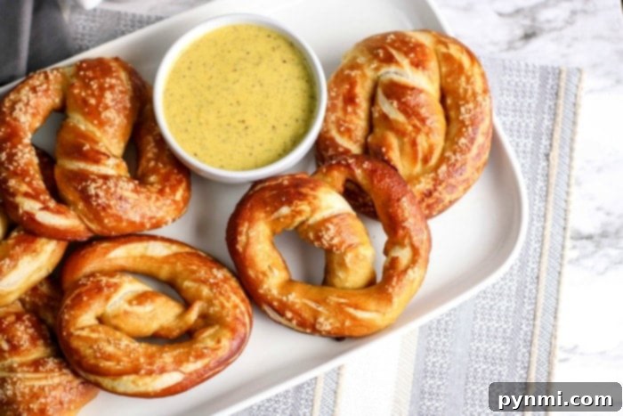 Golden Mustard Pretzel Plunge 5 A large platter of soft pretzels and pretzel bites, perfectly arranged around a bowl of creamy honey mustard dipping sauce, ready for a group.