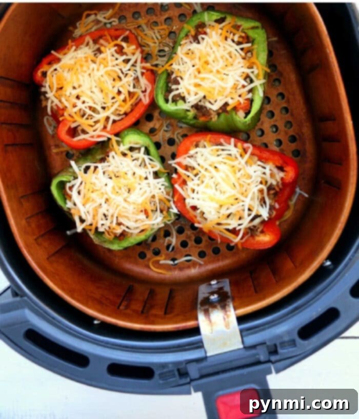 Perfect Air Fryer Stuffed Peppers 2 Four halves of vibrant bell peppers stuffed with ground meat and cheese, perfectly cooked in an air fryer.