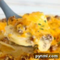 Close-up of a cheesy ground beef casserole with potatoes being served with a spatula.