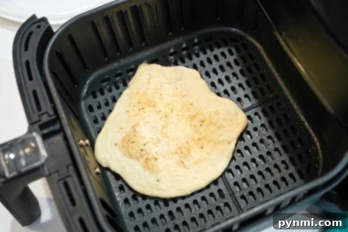 Golden Air-Fried Tortillas 9 A perfectly cooked tortilla rests inside an air fryer basket, showcasing the golden-brown edges and soft center achieved by air frying.