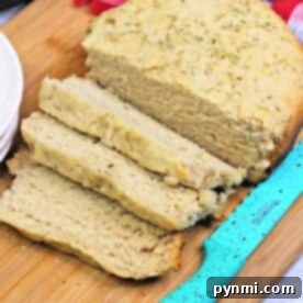 A loaf of slow cooker bread, partially sliced, rests on a wooden cutting board beside a blue-handled knife.