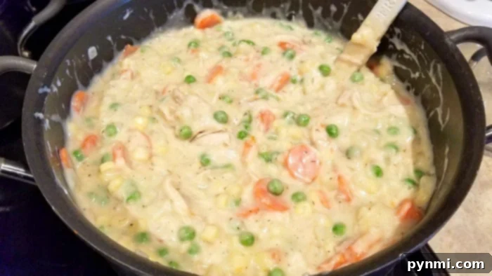 The savory filling for a turkey pot pie simmering in a skillet, showcasing the creamy texture and vibrant vegetables.