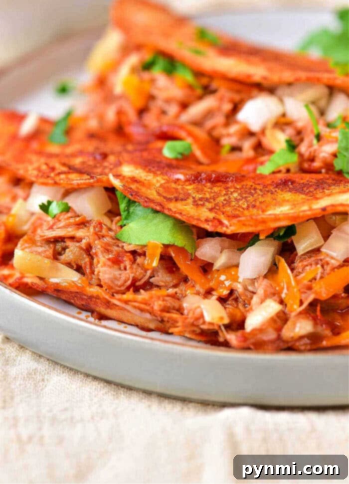 Shredded Crockpot Taco Chicken 2 Succulent Crockpot Chicken Taco Meat, shredded and ready for serving, piled high in a white bowl with cilantro garnish.