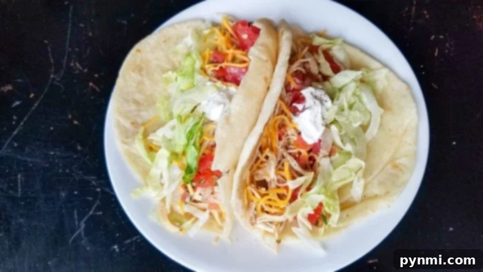 Shredded Crockpot Taco Chicken 5 A plate of chicken tacos with fresh toppings and a side of rice, showcasing the versatility of the slow cooker chicken.