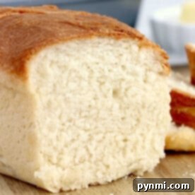 Close-up of a golden brown crusted loaf, its soft white interior revealing the magic of air fryer bread. Nestled on a wooden surface, it invites you to savor its perfect blend of texture and flavor.