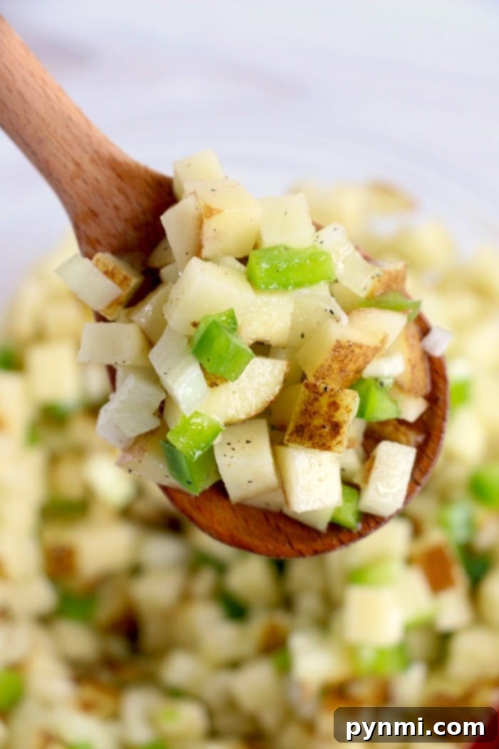 Air fryer diced potatoes with bell peppers topped with cheese are great with eggs, or make breakfast for dinner some night! Cheap and full of flavor. A serving of air fryer breakfast potatoes, beautifully diced and seasoned, awaiting the final cheese topping.