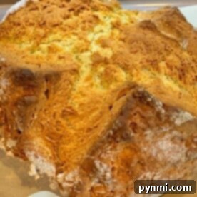 Close-up of freshly baked, golden-brown No Yeast Irish Soda Bread with a cracked crust resting on parchment paper.