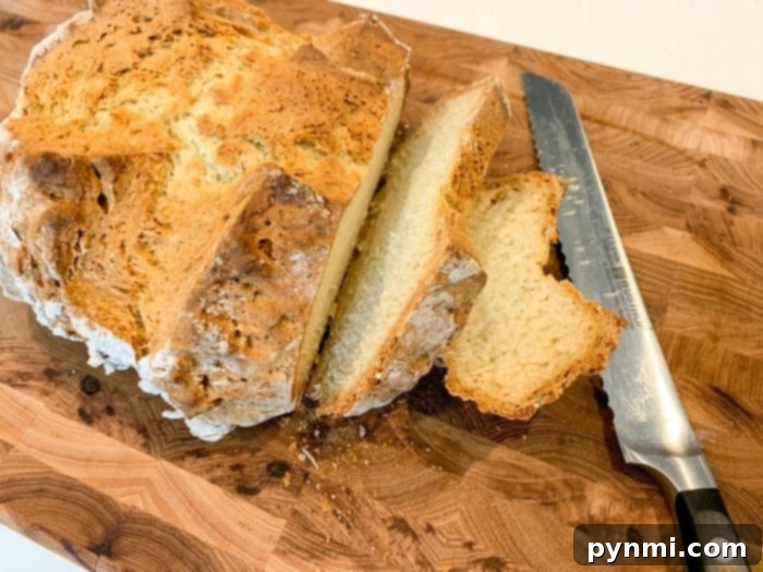 A freshly baked Irish soda bread loaf, golden brown and rustic, cooling on a wooden surface.