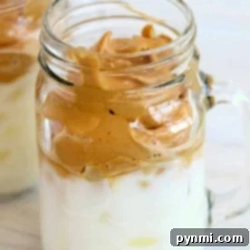 A creamy dalgona whipped coffee delight, elegantly served in a mason jar with its signature frothy crown gracefully resting atop chilled milk.