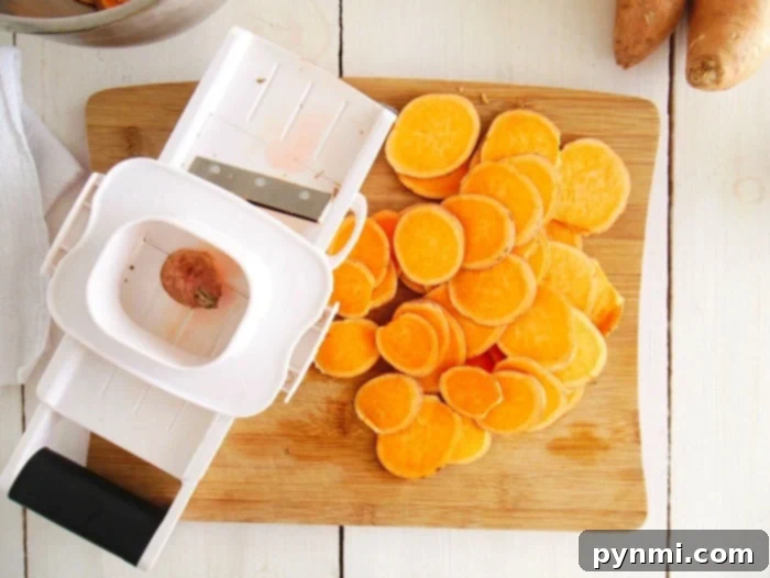 Thinly sliced sweet potatoes ready for the air fryer, illustrating the uniform thickness achieved with a mandoline.