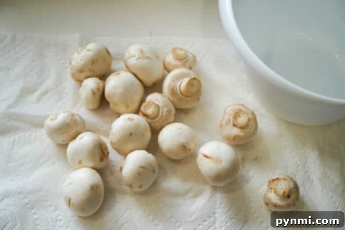 White button mushrooms scattered on a paper towel, perfect for air frying.