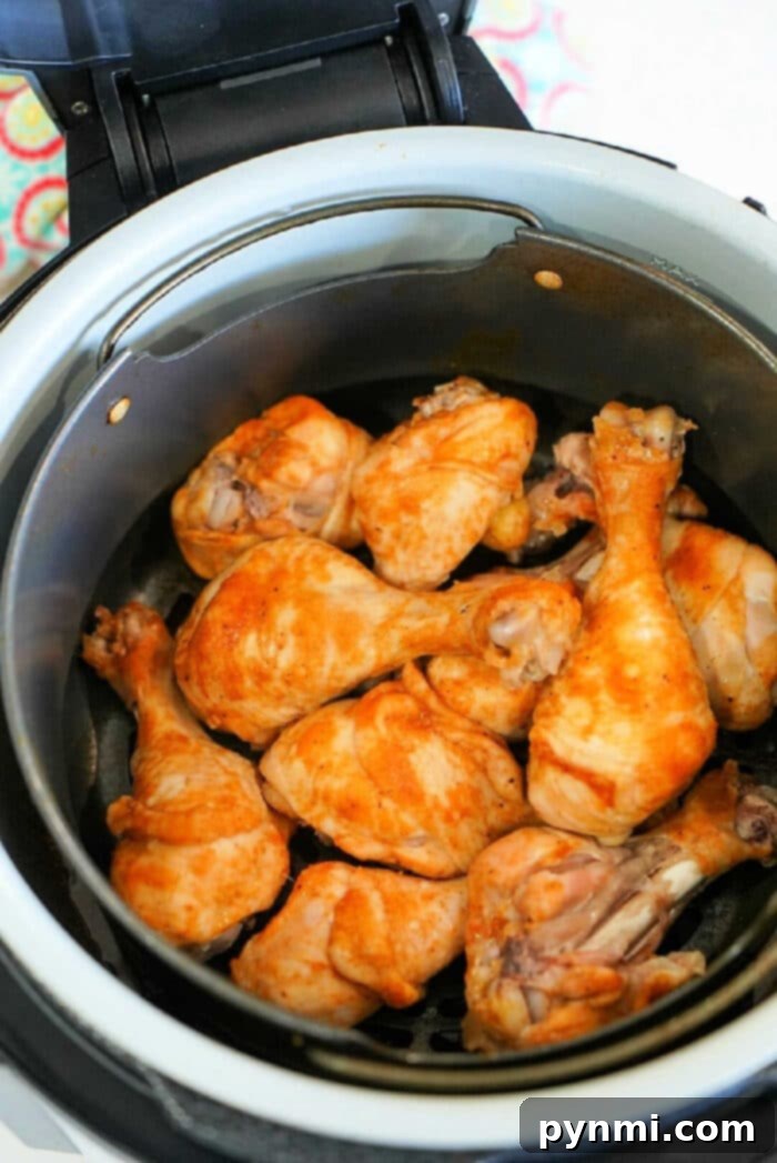 Chicken drumsticks with a golden-brown crust inside a Ninja Foodi air fryer basket.