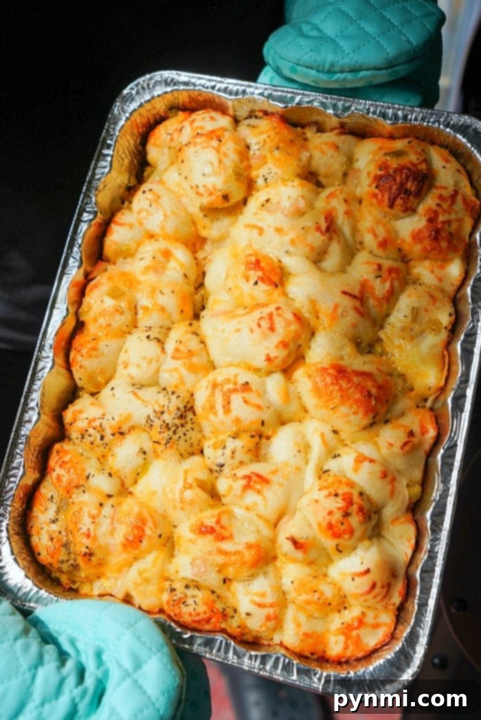 Golden-brown cheesy pull-apart smoked bread fresh off the smoker, glistening with melted cheese and herbs.