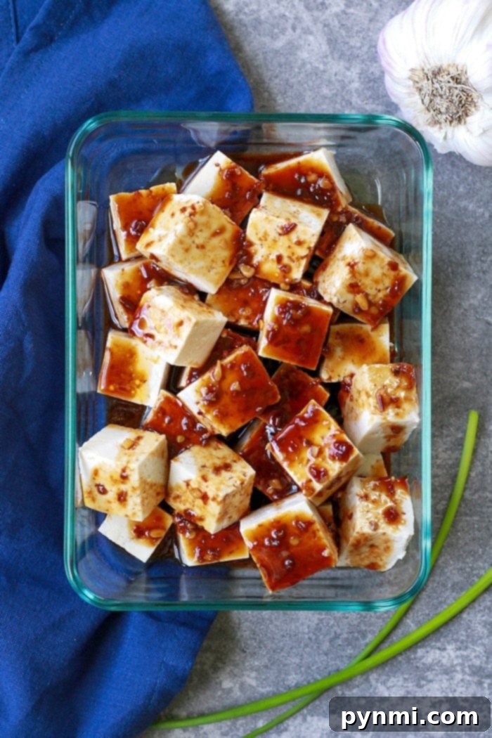 Tofu cubes marinating in a flavorful Asian sauce in a bowl