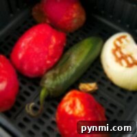 Learn how to roast tomatoes, jalapeños, onions, and garlic cloves effortlessly in an air fryer basket for homemade salsa.