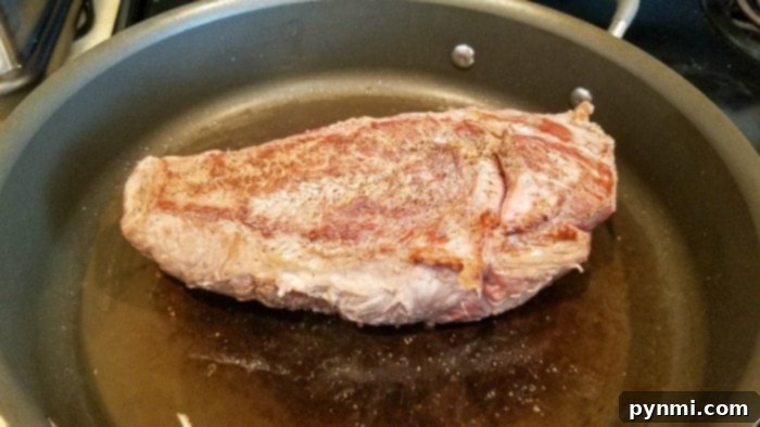 Seared chuck roast in a hot skillet before transferring to a slow cooker.