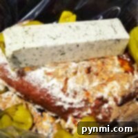 A seasoned Mississippi roast in the slow cooker is topped with a block of herb butter and sliced green peppers for an indulgent dish.
