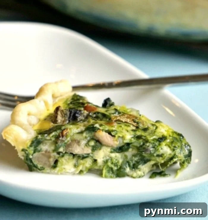 A perfectly portioned slice of easy spinach quiche with visible ingredients, served on a white plate