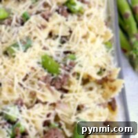 This delectable asparagus pasta recipe features baked pasta with ground meat and cheese, elegantly served in a glass dish.