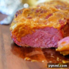 Close-up of a sliced corned beef brisket with a golden crust on a wooden cutting board, hinting at smoky Traeger flavors.