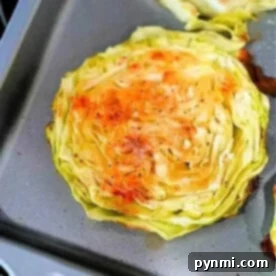 Baked cabbage steaks rest on a baking tray, perfectly seasoned with spices and boasting deliciously browned edges.