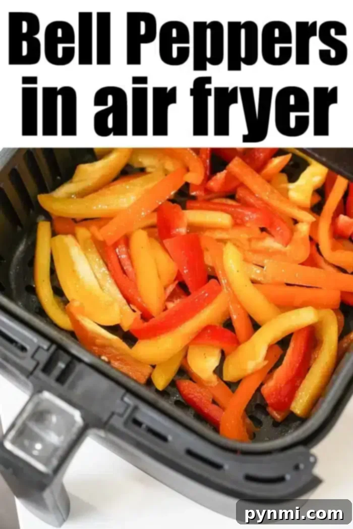 Sliced red, yellow, and orange air fryer peppers are delicately arranged inside the basket, ready for cooking. The text 
