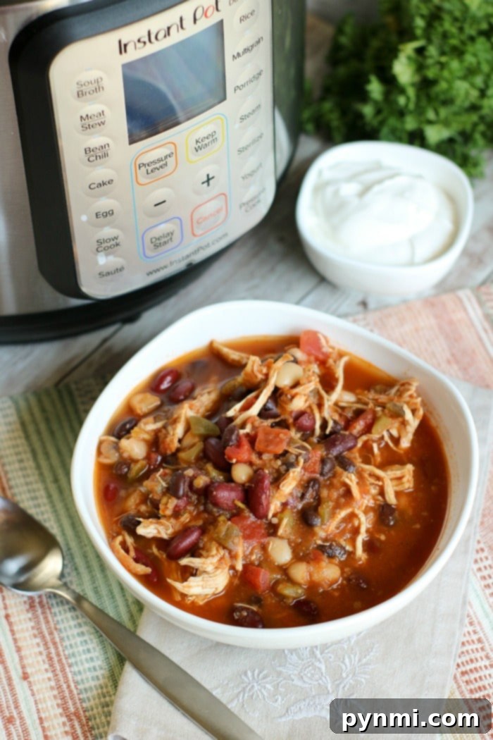 Hearty Instant Pot Chicken Chili 7 Instant Pot Three Bean Chicken Chili, garnished with cheese and herbs.