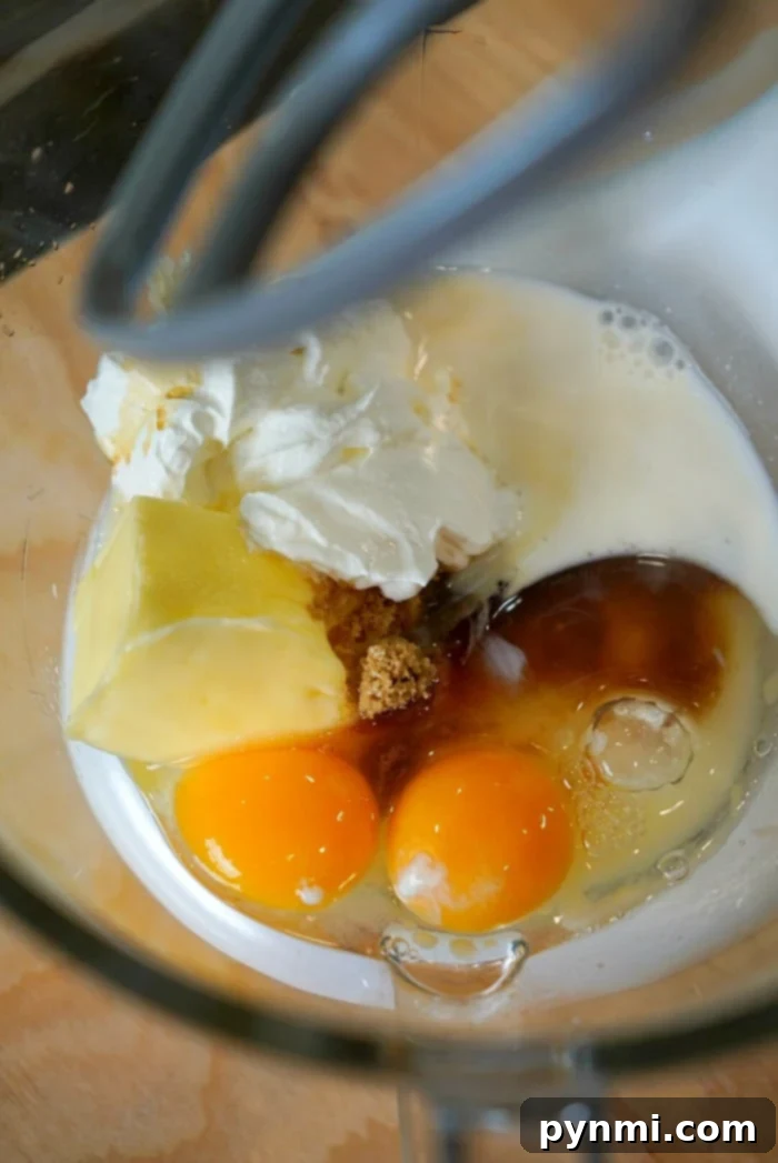 Close-up of wet ingredients for muffin batter in a clear glass bowl, showcasing the creamy mixture before dry ingredients are added.