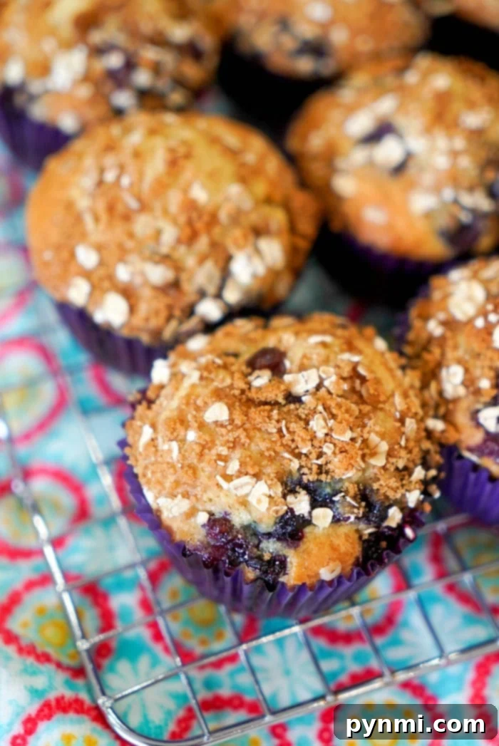 Close-up of huckleberry muffins with crumb topping on a cooling rack, showcasing the easy muffin recipe over a colorful patterned cloth.