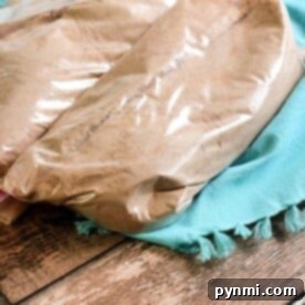 Two plastic bags filled with homemade cake mix, sit on a turquoise cloth on a wooden surface.