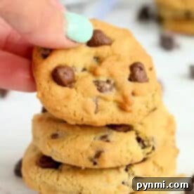 Air Fried Chocolate Chip Perfection 7 A hand with mint-green nail polish holds a chocolate chip cookie above a stack of air fryer cookies.