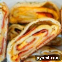Close-up of sliced stromboli with layers of cheese and pepperoni, showcasing a tantalizing twist reminiscent of a Traeger pizza, all beautifully arranged on a white plate.