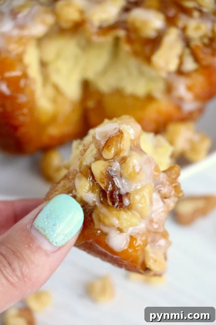 Easy Air Fryer Monkey Bread 2 A hand with mint green nails holds a piece of glazed air fryer monkey bread creation.