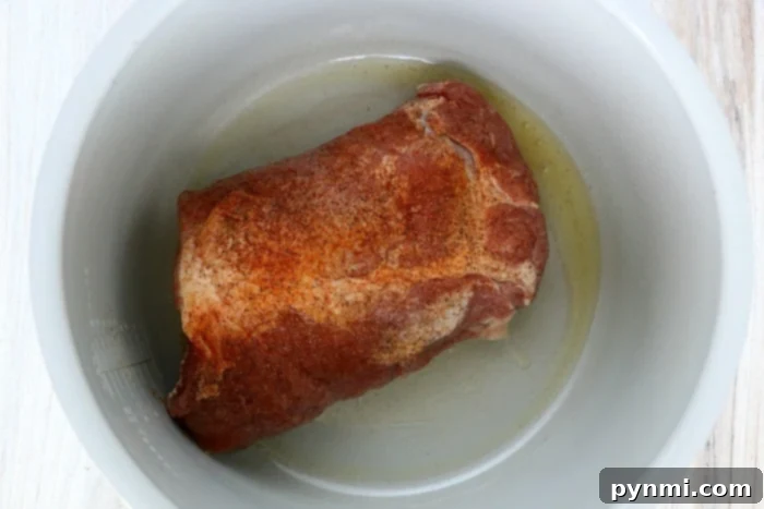 Ninja Foodi Shredded Pork Perfection 4 Seasoned pork butt in a pressure cooker pot coated with oil, perfect for creating scrumptious Ninja Foodi pulled pork.