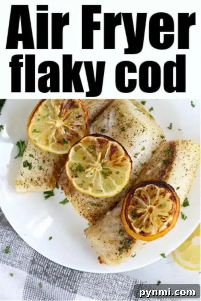 A plate of air fryer fish cod fillets is garnished with slices of lemon and sprigs of parsley. The fish appears to be seasoned with pepper and herbs.
