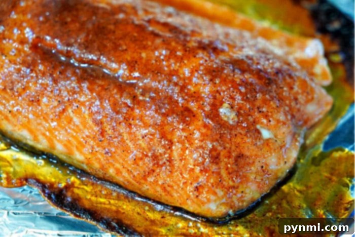 A whole baked salmon fillet, beautifully golden brown from the dry rub, garnished with fresh herbs and a lemon wedge, ready to be served.