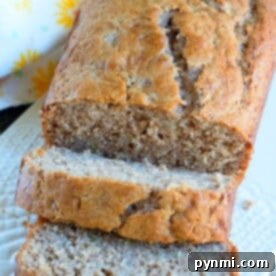 Mayonnaise Magic Banana Bread 9 A sliced loaf of banana bread with mayonnaise on a white plate, complemented by a floral napkin in the background.