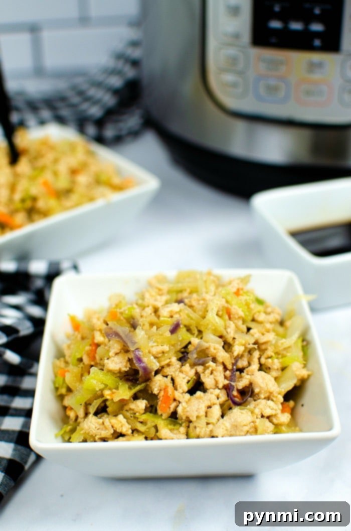 Speedy Instant Pot Egg Roll Bowls 6 A vibrant bowl of deconstructed egg roll, with ground meat, shredded cabbage, and carrots, garnished with fresh green onions.