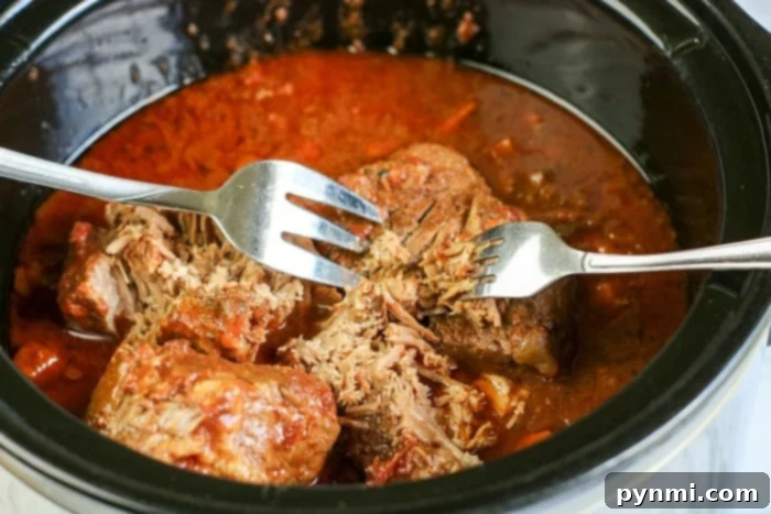 Effortless Slow Cooker Sunday Sauce 7 pulled beef in slow cooker – Shredded beef ragu simmering in a slow cooker, showing the tender, pulled beef texture.
