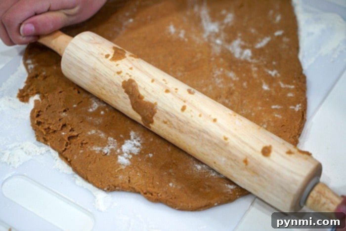 Cake Mix Hack for Air Fryer Gingerbread Cookies 6 A person meticulously rolling out gingerbread cookie dough on a lightly floured cutting board.