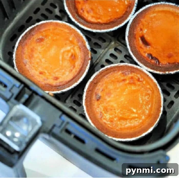 Easy Mini Pumpkin Pie Recipe 2 Four mini air fryer pumpkin pies in foil tins sit perfectly inside the basket, ready for a delicious and easy treat.
