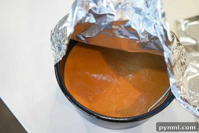 Easy Mini Pumpkin Pie Recipe 7 A bowl of crustless pumpkin pie, partially covered by aluminum foil on a white surface, highlighting a healthier dessert option.