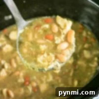 Creamy Crockpot White Chicken Chili 6 Ladle scooping easy white chicken chili from a crockpot, showing a generous portion.