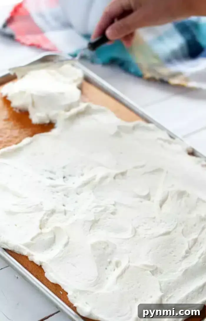 Effortless Half Sheet Cake Perfection 2 A tray of 1/2 sheet cake is being frosted with white icing.