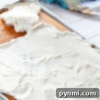 Spreading white frosting smoothly over a 1/2 sheet cake with a spatula.