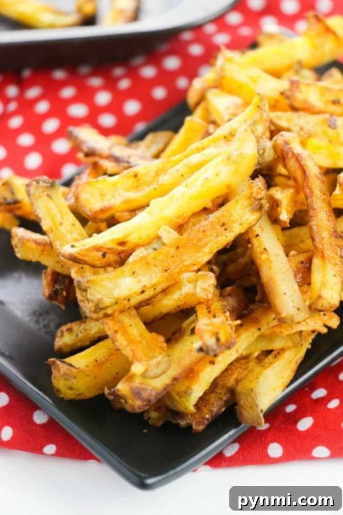 A large serving of golden brown, crispy homemade French fries on a dark plate.