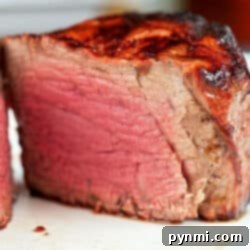 A close-up of a thick, juicy, medium-rare air fryer filet mignon with a seared crust and pink center.